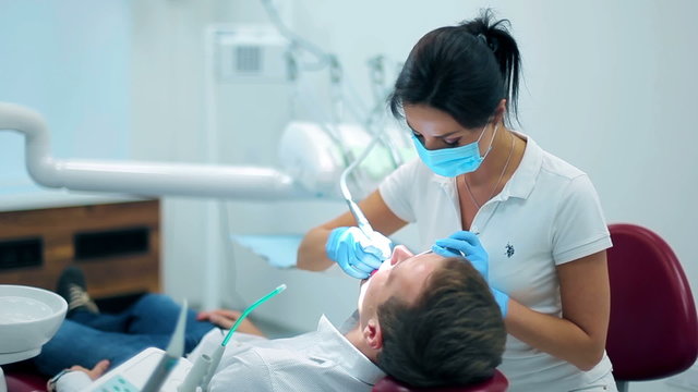 Professional dentist installing fillings patient