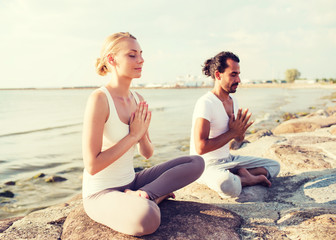 smiling couple making yoga exercises outdoors