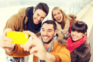 Obraz premium happy friends with smartphone on skating rink