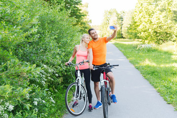Obraz premium couple with bicycle and smartphone taking selfie