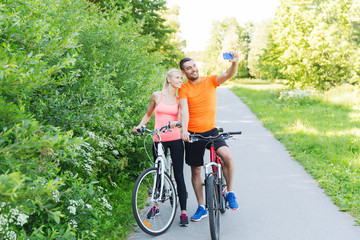 couple with bicycle and smartphone taking selfie