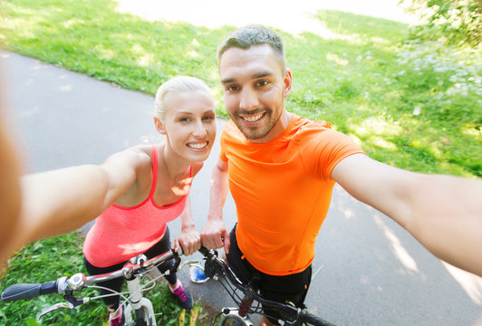 couple with bicycle taking selfie outdoors