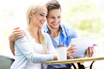 Couple using digital tablet at cafe

