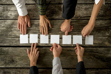 Seven hands of business people  placing seven white cards in a r