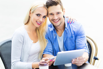 Couple using digital tablet at cafe
