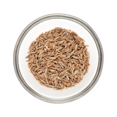 Top view of Organic Cumin seed (Cuminum cyminum) half filled in glass bowl isolated on white background.