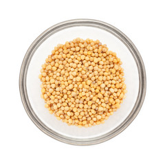 Top view of Organic yellow mustard (Brassica alba) half filled in glass bowl isolated on white background.