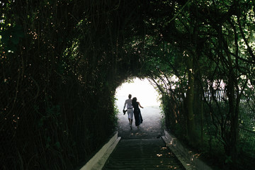 couple walking through the tunnel of trees