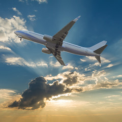 Fototapeta na wymiar Commercial airplane flying with clouds and sun rays background