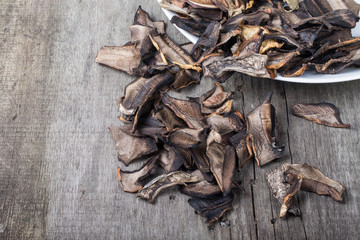 Pieces of dried porcini mushrooms on ceramic plate on old gray w