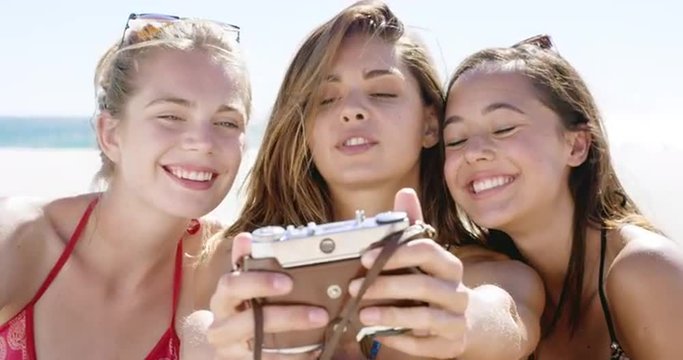 Close up of three teenage girl friends taking selfie photograph with vintage camera