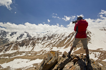 Naklejka na ściany i meble man on a cliff in mountains making photo