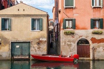 Fototapeta na wymiar Narrow alley in Venice and red boat
