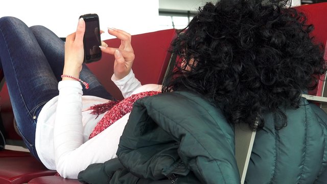 4k Busy businesswoman surf internet on smartphone lying relaxed at airport, train, bus station waiting for departure look from behind.  UHD stock footage