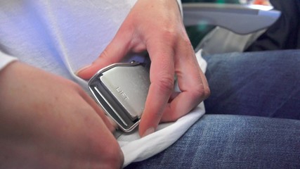 4K View of the woman fastening her seat belt. Safe travel is of great importance while traveling in airplane. UHD stock footage