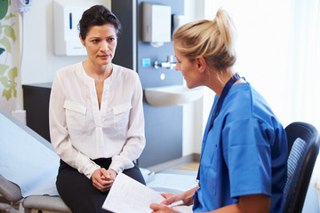 Female Patient And Doctor Have Consultation In Hospital Room