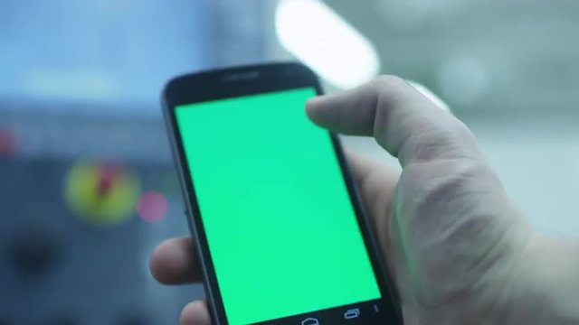 Worker is Using Smartphone With Green Screen in Portrait Mode in Factory. Great For Mock-Up Usage.