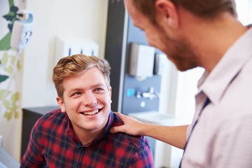 Fototapeta premium Male Patient Being Reassured By Doctor In Hospital Room