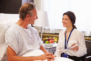 Female Doctor Talking To Male Patient In Hospital Bed