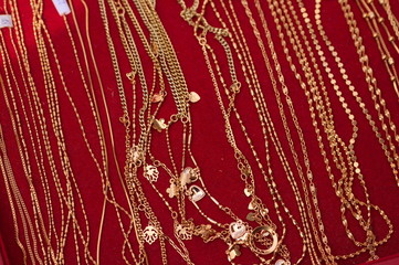 Złote łańcuszki biżuteria na czerwonym tle