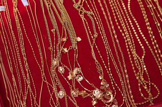 Złote łańcuszki biżuteria na czerwonym tle