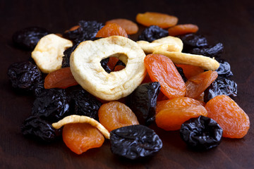 Pile of mixed dried fruit isolated on dark wood. In perspective.