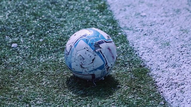 Close-up shot of used and old soccer ball on the field