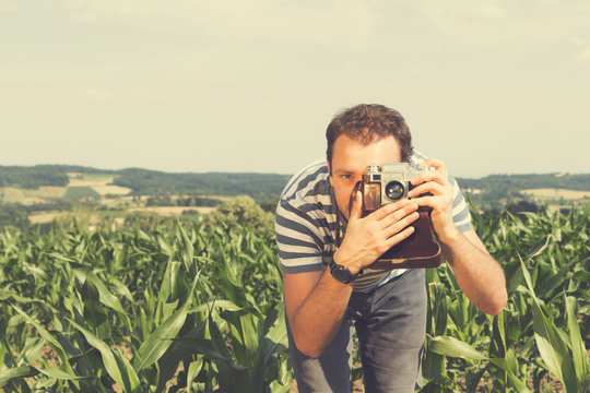 Young hipster man photographing with vintage camera.