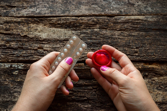 young woman holding a birth control pills and a condom