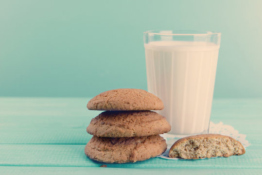 Tasty cookies and glass of milk on table on turquoise background