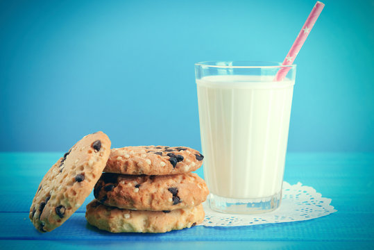 Tasty cookies and glass of milk on table on blue background