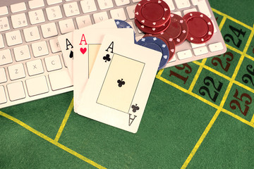 Trio of aces with poker pieces on a computer keyboard and green carpet