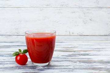 Glass of tomato juice with vegetable on wooden background