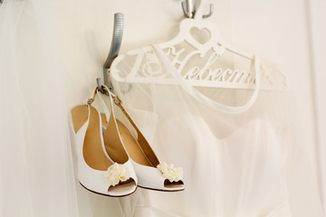 Bride dress and shoes is on the decorated hanger 
