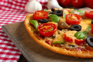 Tasty pizza with vegetables and basil on table close up