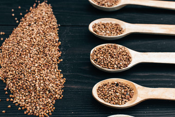 buckwheat groats and wooden spoon on the black table