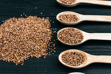 buckwheat groats and wooden spoon on the black table