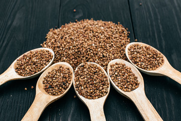 buckwheat groats and wooden spoon on the black table