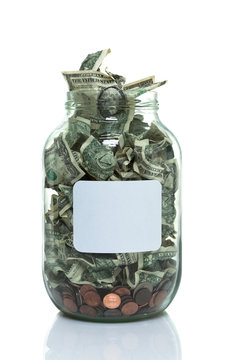 Glass jar full of money with a white label