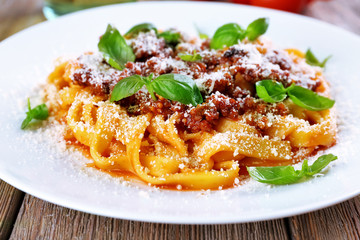 Pasta Bolognese with parmesan and basil on plate close up