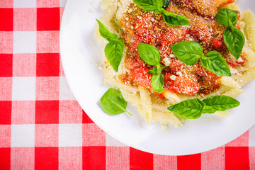 Pasta with tomato sauce and basil on table close up