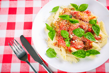 Pasta with tomato sauce and basil on table close up