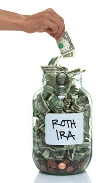 Hand putting money into a savings jar with a white ROTH IRA labe