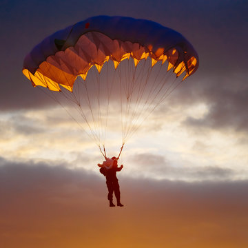 Skydiver On Colorful Parachute In Sunny Sky