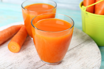 Glasses of carrot juice with vegetables on wooden background