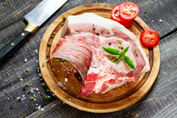 Raw meat ribs bone steak, pork with basil and tomatoes on a cutt