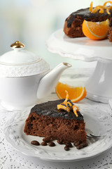 Cake with Chocolate Glaze and orange on plate, on wooden table, on light background