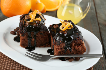Portion of Cake with Chocolate Glaze and orange on plate, on wooden background
