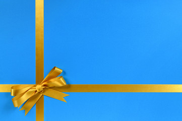 Gold gift bow and ribbon for christmas or birthday present on a blue wrapping paper background photo