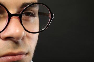 Attractive young man with glasses on gray background